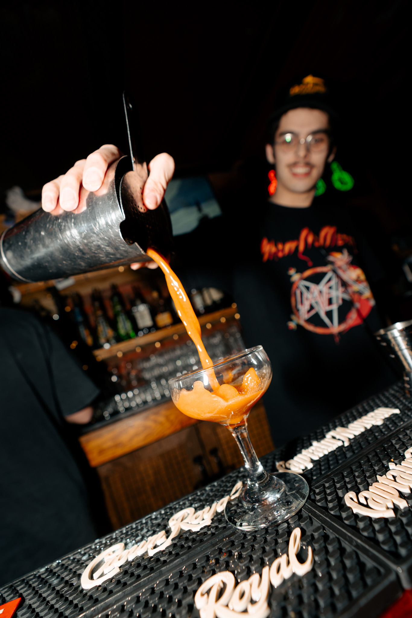 Bartender pouring an orange cocktail behind the Warehouse bar.