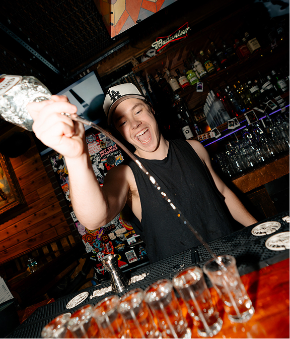 Bartender pouring a round of shots behind the Warehouse bar.