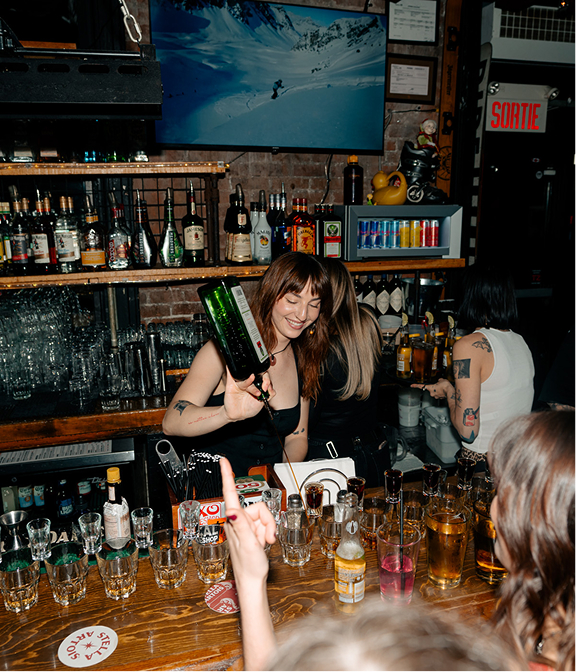 Bartender pouring shots for guests at a busy Warehouse bar.
