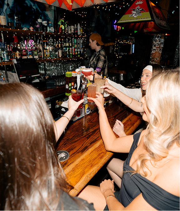 Group of friends raising cocktails for a toast at the Warehouse bar.