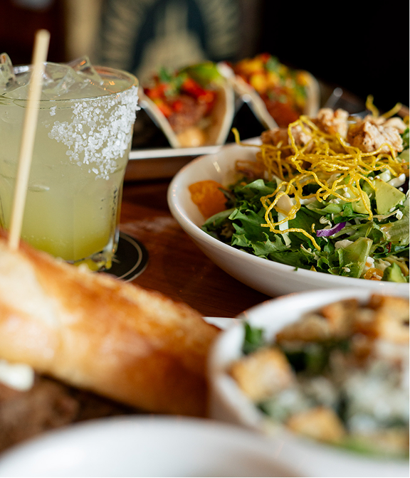 Margarita served with tacos, salad, and burgers on a Warehouse table.