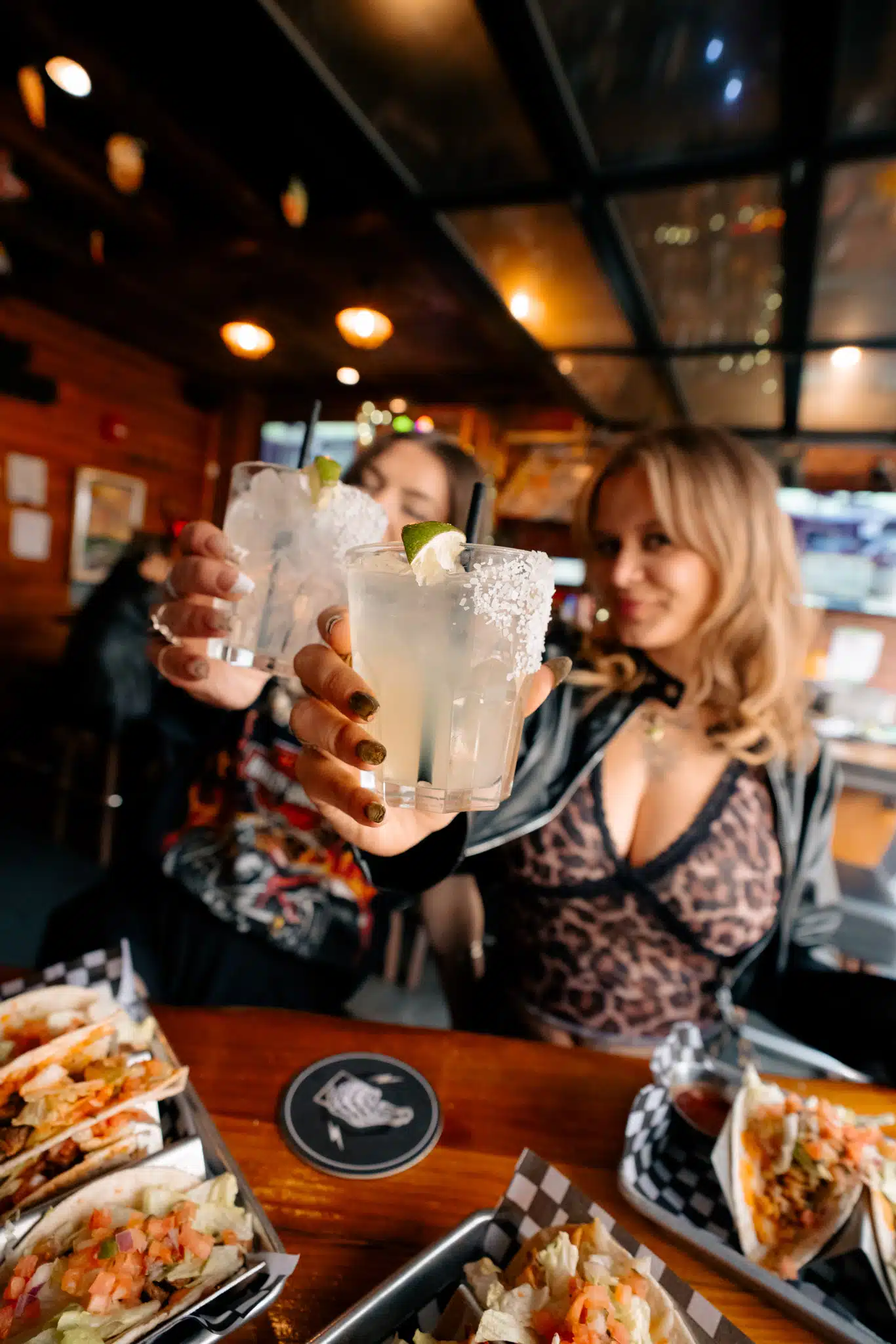 Friends raising margaritas over tacos and share plates at Warehouse.