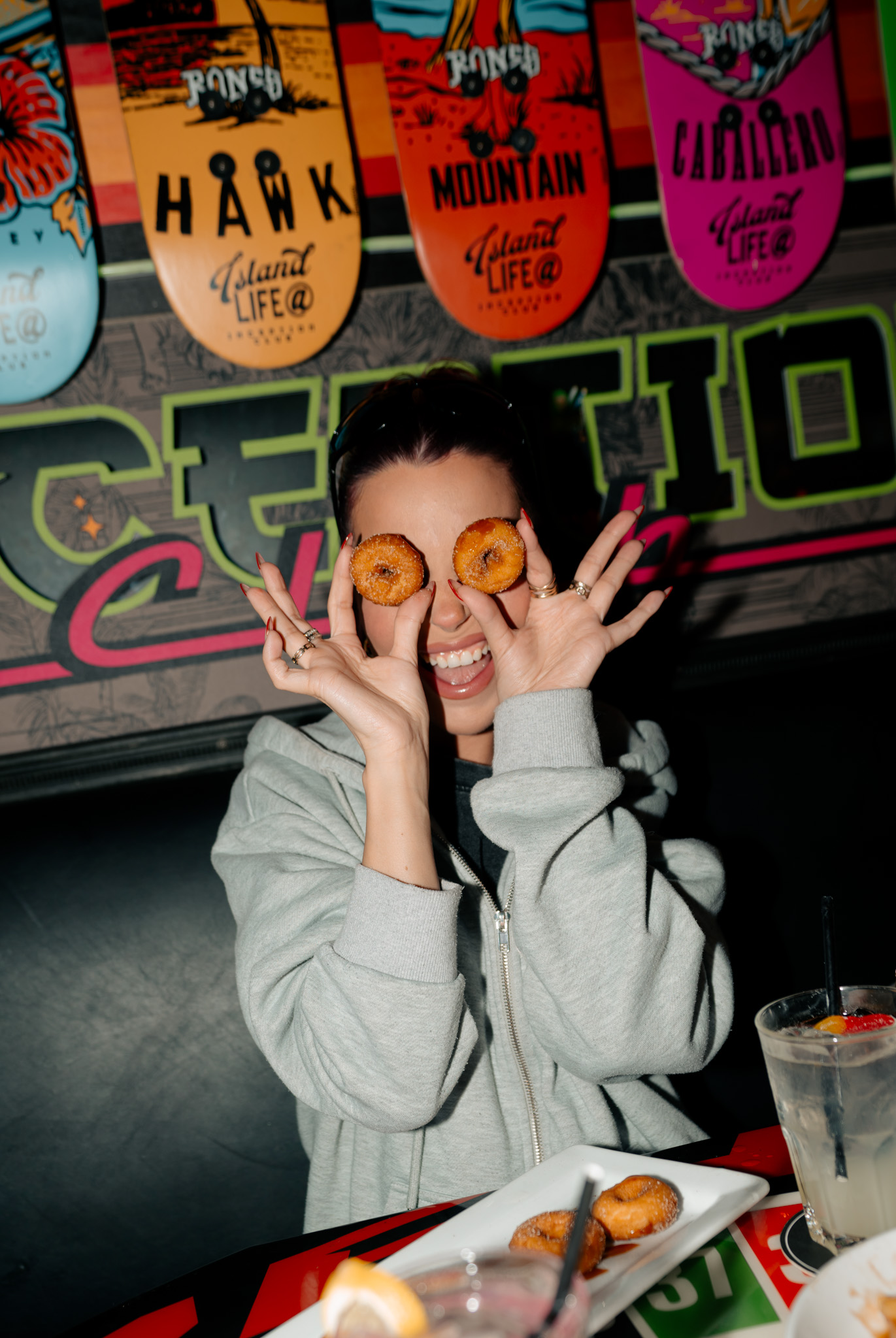 Guest posing with mini donuts and a drink during a night out at Warehouse.