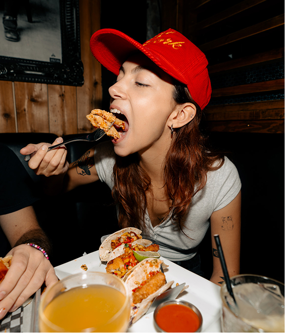 Guest eating tacos with drinks on the table at Warehouse.