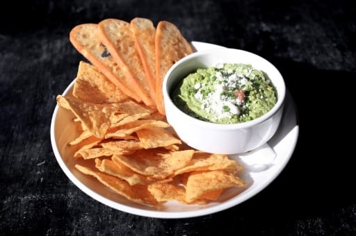 A bowl of creamy spinach dip with tortilla chips and toasted bread, served at Warehouse Ontario.