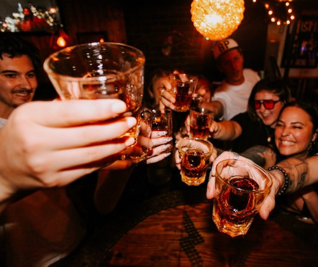 Group clinking Jagerbombs in warmly lit Warehouse bar with cozy amber lights in Whistler.