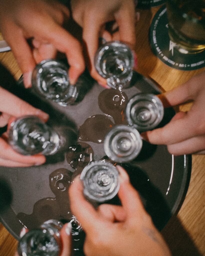 Group of five friends raising shot glasses in a celebratory toast inside Warehouse’s energetic Seattle location.