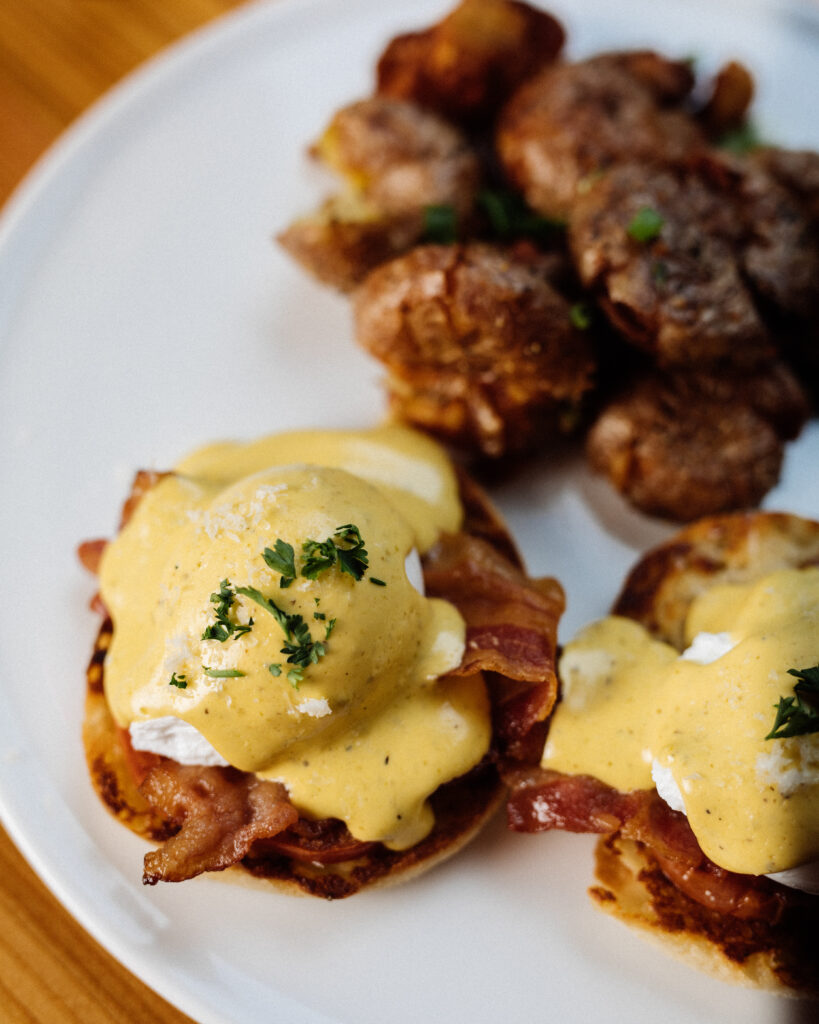 Plate of Eggs Benedict with crispy smashed potatoes served at Warehouse brunch in Whistler, BC.