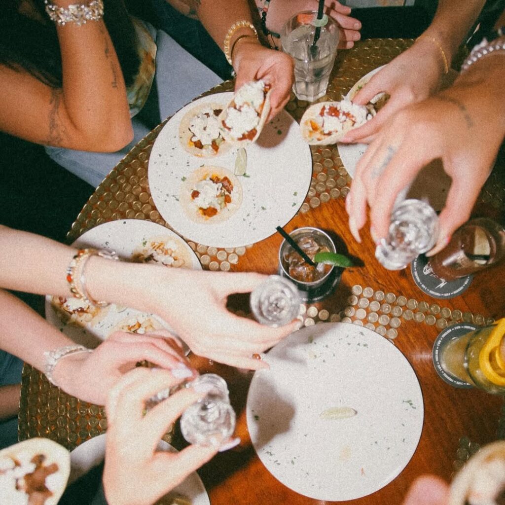 Overhead view of mini tacos, lime wedges, cocktails, and celebratory toast at Warehouse brunch in Whistler.