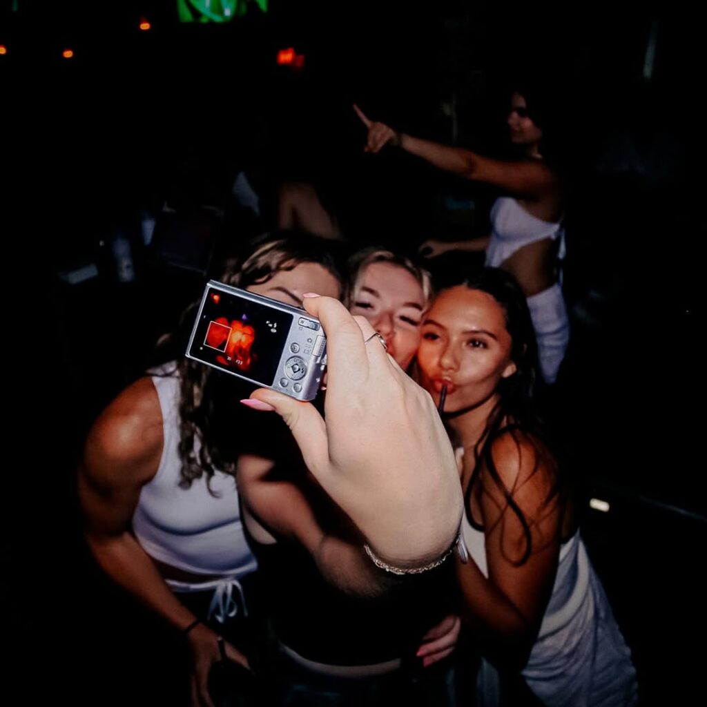 Friends enjoying a lively Warehouse night out, capturing a fun moment with drinks and dancing.