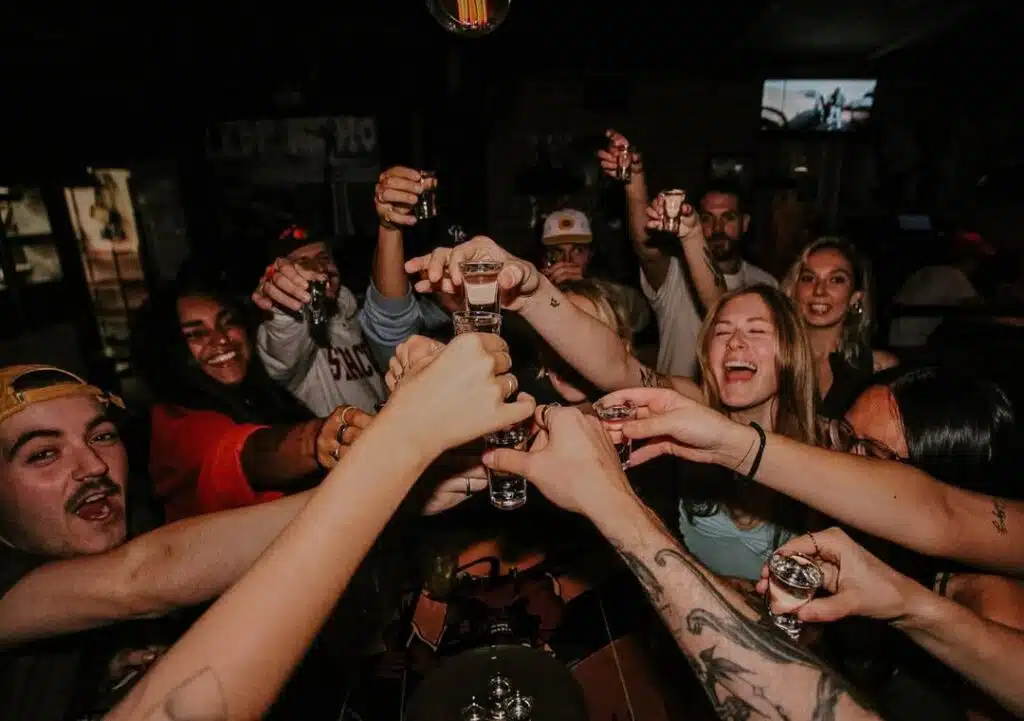 A late-night crowd at Warehouse raising shot glasses together for a wild, shared celebration.