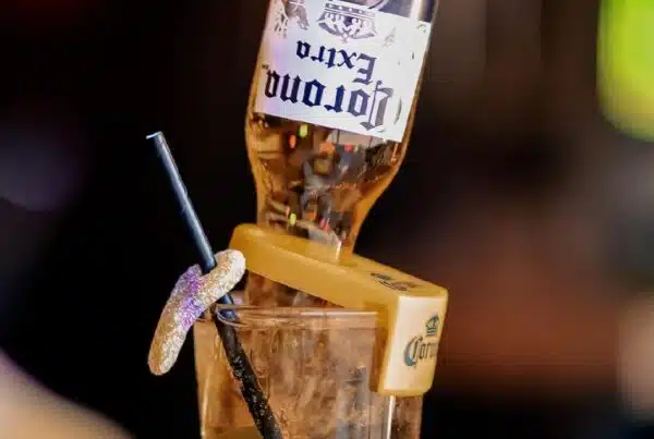 A Corona Extra beer bottle inverted into a sugared-rim glass with a straw, creating a playful and eye-catching cocktail presentation.