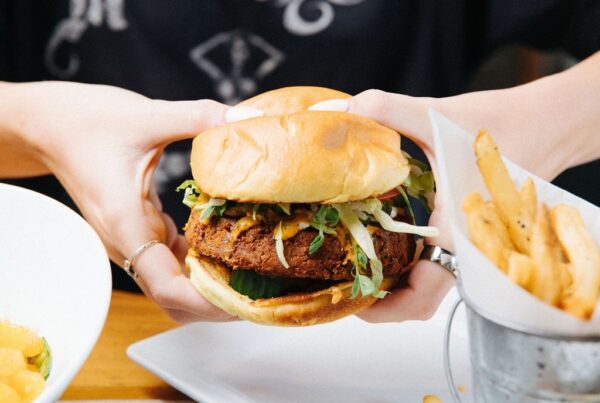 A close-up shot of The Warehouse Veggie burger with a crispy patty and slaw, served with a side of fries.