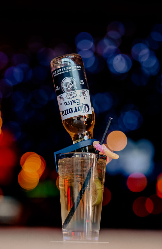 A Corona beer flipped upside-down into a cocktail glass with lime slices, straw, and candy garnish at Warehouse.