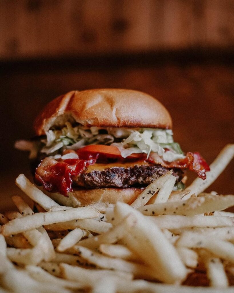 A juicy double-patty burger stacked with toppings, served on a bed of crispy fries at Warehouse.