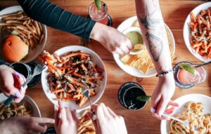 A table filled with food, a bowl of Poutine being shared along with nachos and fries at Warehouse.