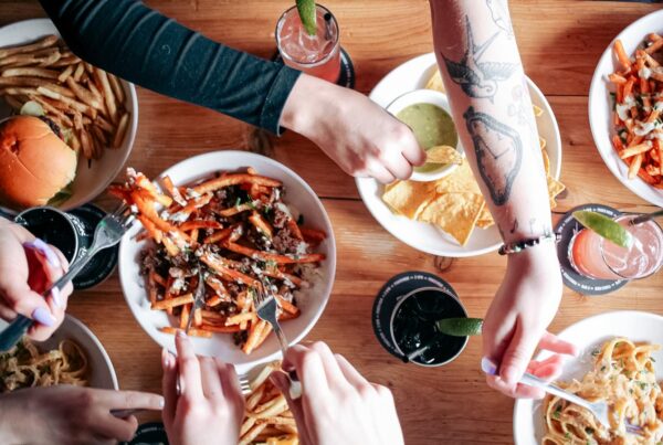 A table filled with food, a bowl of Poutine being shared along with nachos and fries at Warehouse.