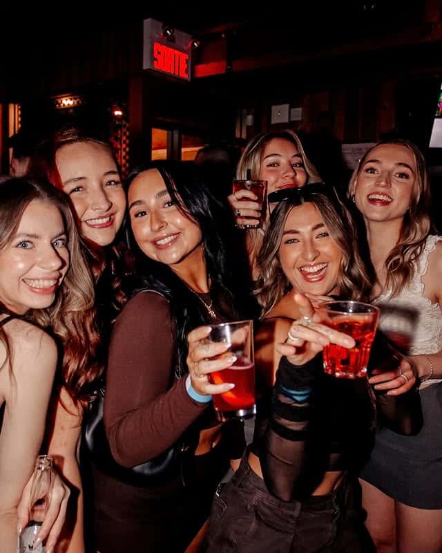 Group of students raising shot glasses together at Warehouse Montreal during happy hour.