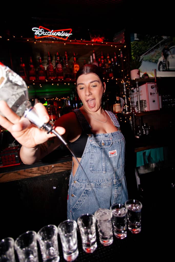 Bartender pouring multiple shots with energy behind the Warehouse bar.
