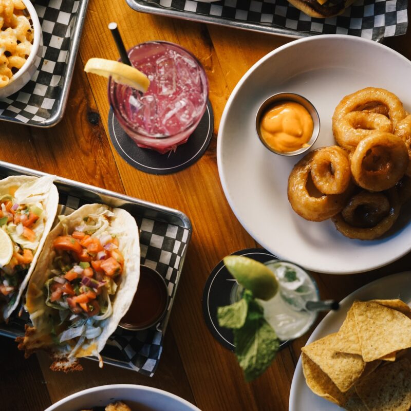Table of tacos, burgers, onion rings, and drinks at Warehouse in Victoria BC.