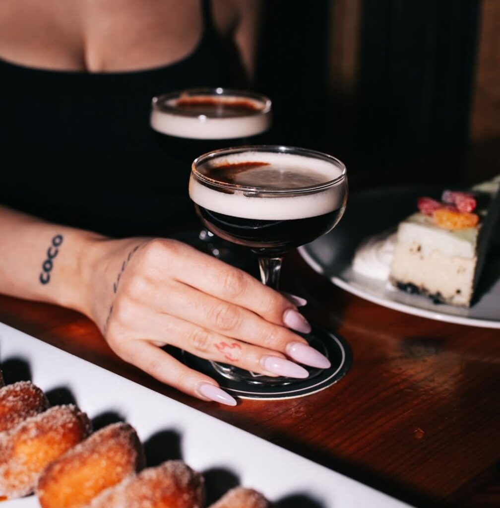 A plate of mini-donuts and a server placing some cocktails on a table at Warehouse.