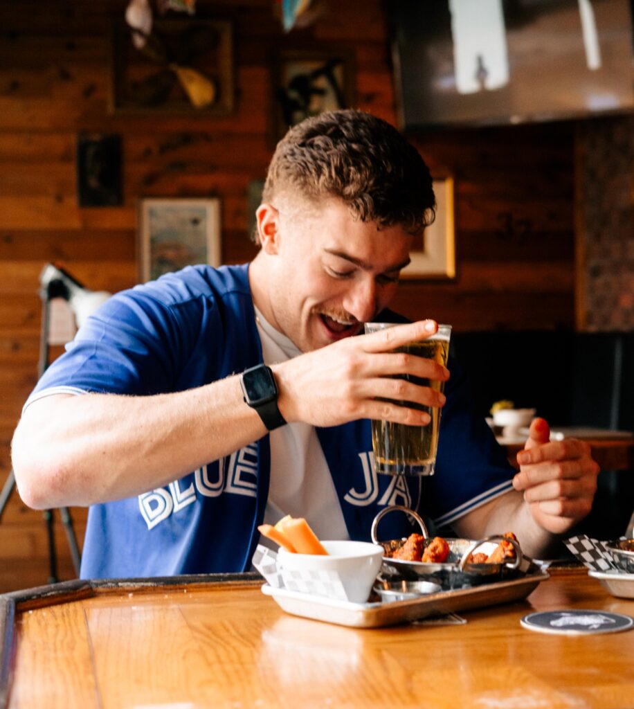  A man wearing the Blue Jays’ jersey and enjoying food and drink at Warehouse, Toronto.