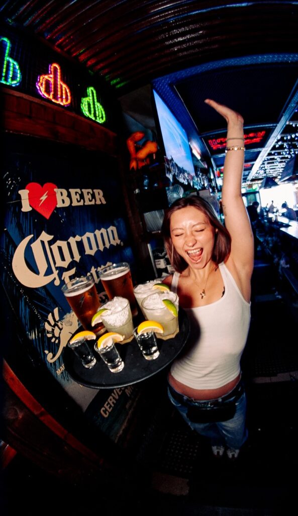 A woman carrying the Warehouse Happy Hour Special drinks on a plate.