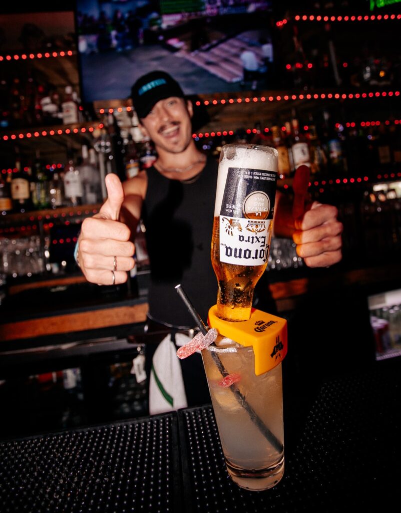 A bar attendant at Warehouse, showing off his drink at the bar counter. 
