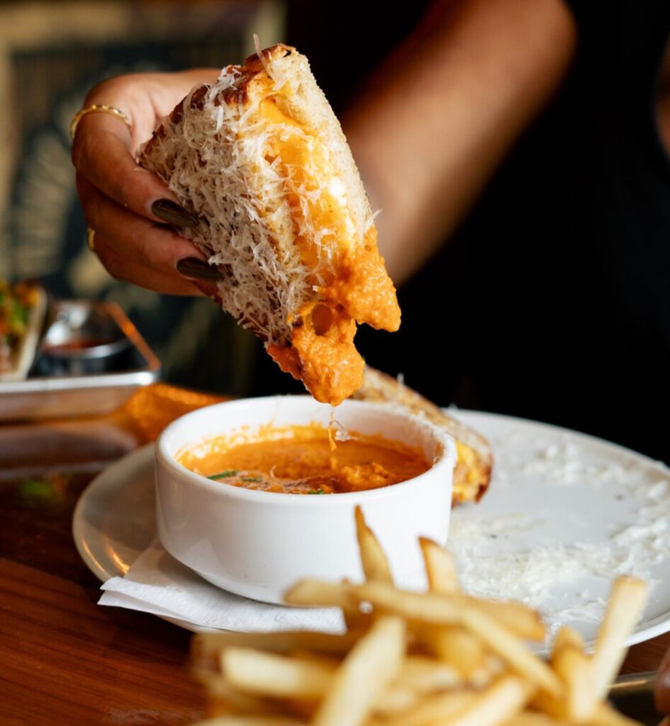 A lady dipping bread into a hot soup at Warehouse. 