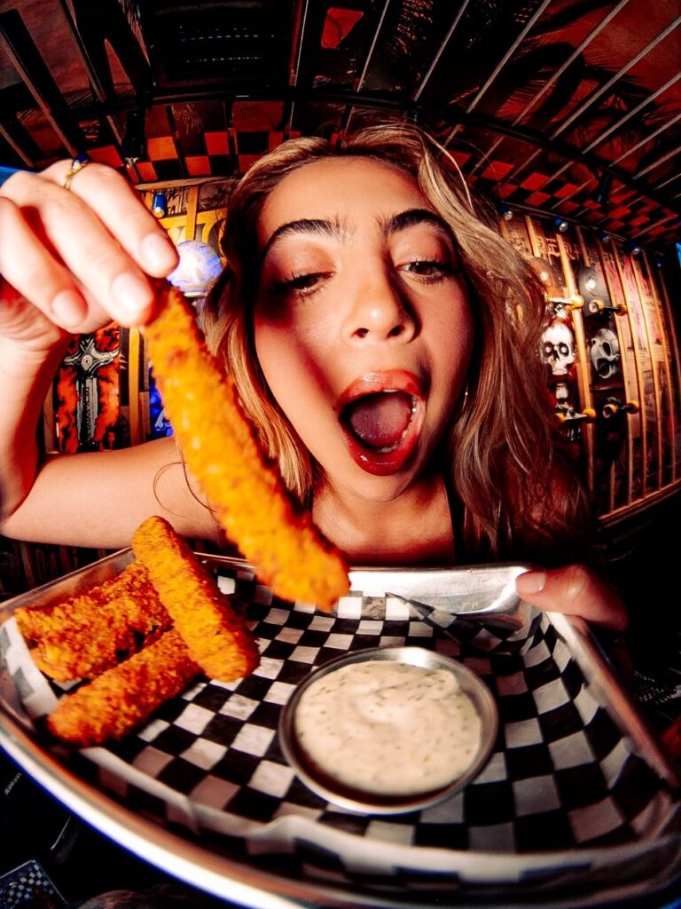 A lady dipping the crunchy chicken strips into a dip inside the Warehouse.