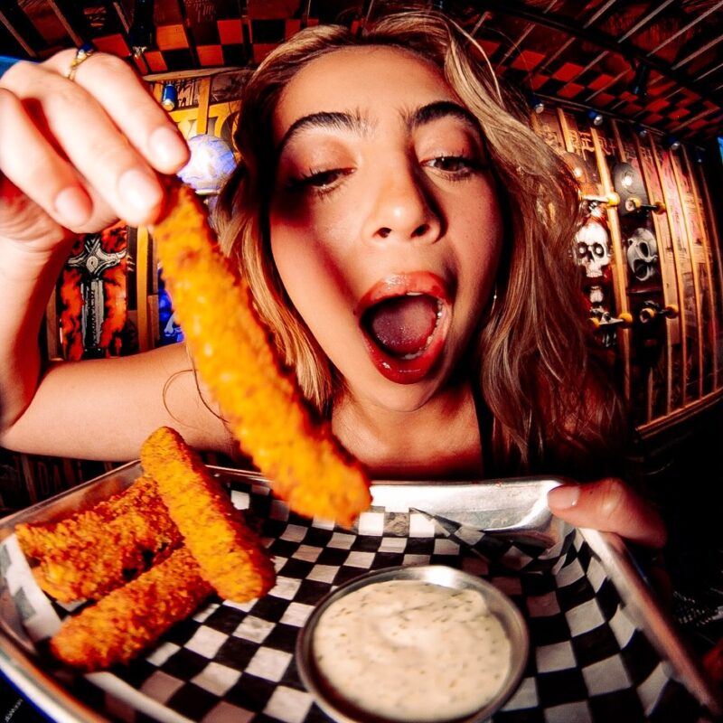 A lady dipping the crunchy chicken strips into a dip inside the Warehouse.