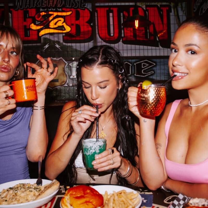 Three women enjoying cocktails and food together at Warehouse
