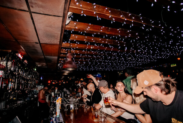 Guests enjoying drinks and conversation inside a lively Warehouse bar featuring a vibrant atmosphere and casual dining setting.