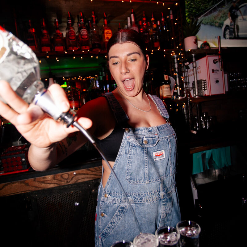 Bartender serving a round of shots to customers at Warehouse during a lively late-night afterparty.
