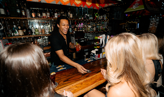 Bartender serving drinks to guests at a busy Warehouse bar.