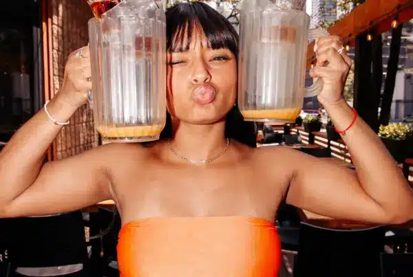 Woman holding two empty cocktail pitchers and posing inside Warehouse.