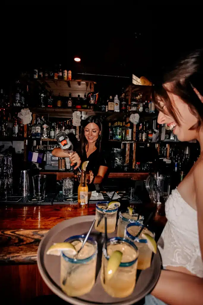 Bartender preparing cocktails while a server carries margaritas to guests at Warehouse.